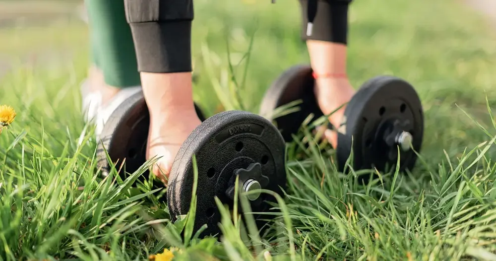 Halteres no gramado, imagem de treino ao ar livre para quem busca sites para achar personal trainer em Ananindeua